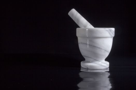 White marble mortar with a pestle on a black background