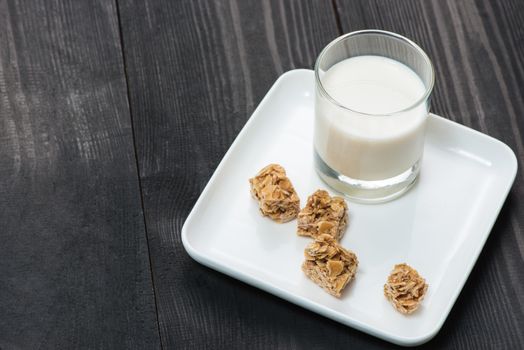 Dairy products. A glass of milk serve with almond candies on a rustic wooden table.