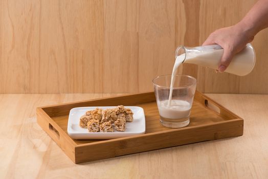 Dairy products. A bottle of milk and glass of milk serve with almond candies on a wooden table.