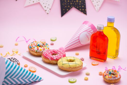 Party. Different colourful sugary round glazed donuts and bottles of drinks on pink background.