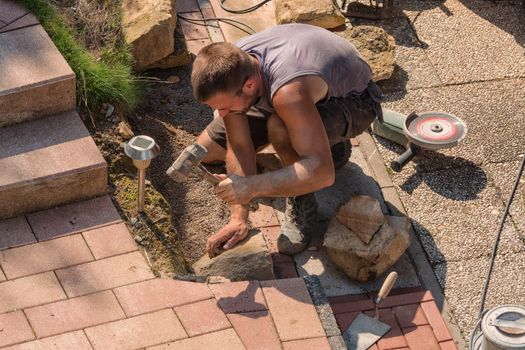 Man Build a dry wall in the garden. In the background, various tools.