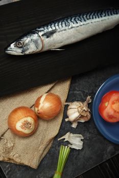 Mackerel and vegetables on a wooden table. Vertical photo