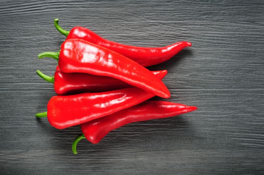 Heap of five ripe sweet red Kapia peppers on dark shale stone background, copy space
