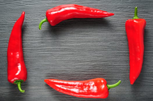 Frame made of four ripe sweet red Kapia peppers on dark shale stone background