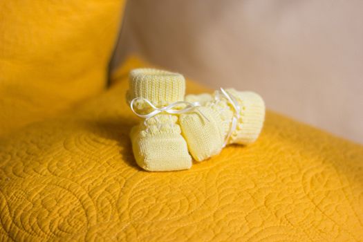 Children's yellow bootees on a yellow pillow
