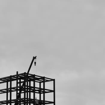 BLACK AND WHITE PHOTO OF SILHOUETTE CONSTRUCTION CRANE