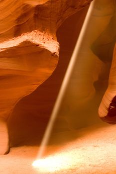 A beam of sunlight shining into Antelope Canyon, near Page, Arizona. Antelope Canyon was created by flash flood waters cascading and swirling through the sandstone chambers of the canyon. The floodwaters erode away the canyon walls to create intracate textures and rock formations. During the day, shafts of light become visible for brief moments as the sun shines overhead.