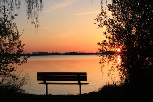 Sunset with bench in early spring Lake Erie