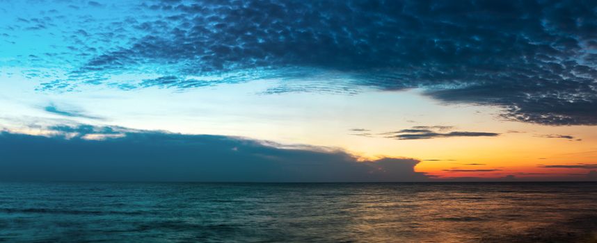 Panorama fantastic clouds against blue sky over sea in sunset time