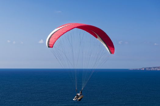 Colorful hang glider in sky over blue sea 