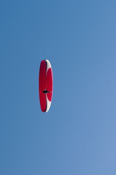 Colorful hang glider in sky over blue.