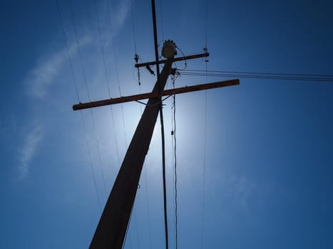 Silhouetted  electric post in blue sky background