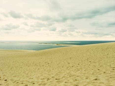 Sand dunes, sea and cloudy sky. Dune of Pilat (Dune du Pilat), the biggest sand dune in Europe, located in the Arcachon Bay area, France.