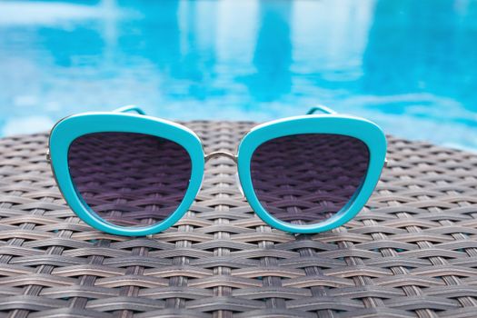 Summertime sunglasses relax near swimming pool.
