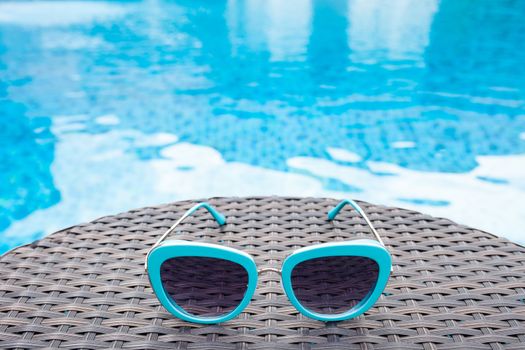 Summertime sunglasses relax near swimming pool.