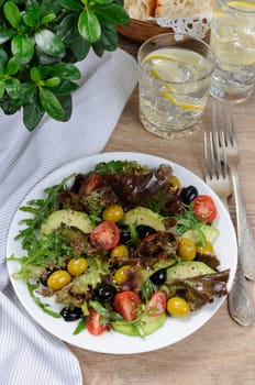 Summer salad - with avocado, olives, tomatoes in lettuce dressed, mustard-garlic sauce