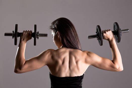 Sexy girl in short black dress, posing and lifting weights