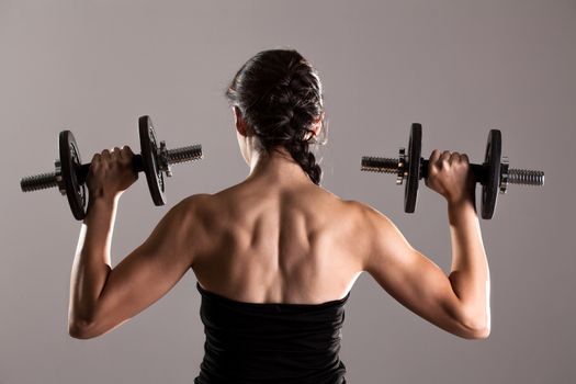 Sexy girl in short black dress, posing and lifting weights