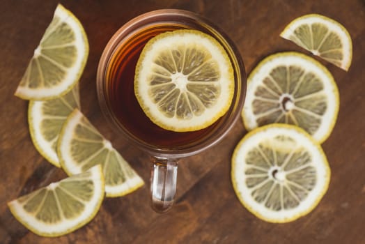 Top view of black tea with lemon in cup on wooden plank table.