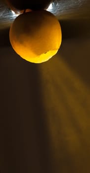 ripe yellow apple shine through with volumetric light on black background.