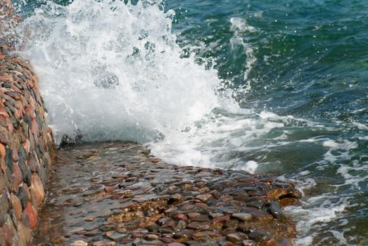 Photo of beautiful clear turquoise sea ocean water surface with ripples and bright splash on stone seascape background, horizontal picture.