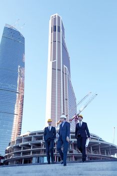 Architects with blueprint at skyscrapers background