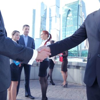 Business handshake, the deal Is finalized by group of people outside