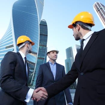 Investor and contractor shaking hands, view from below