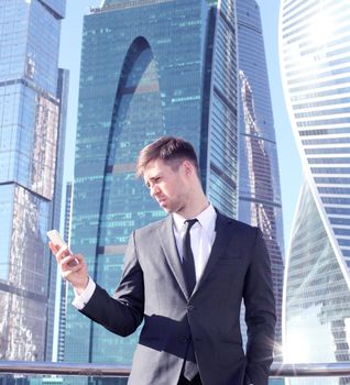 Businessman using smartphone on skyscraper background