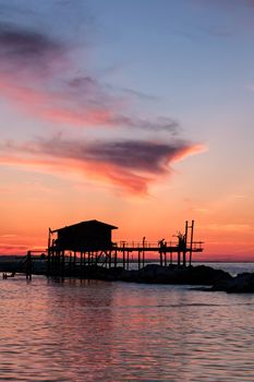 Stilt house in silhouette over the sea during a beautiful red sunset