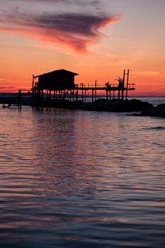 Stilt house in silhouette over the sea in a beautiful red sunset