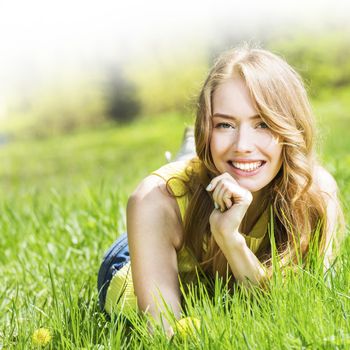 Redhead or blonde romantic beautiful young woman laying on grass in park