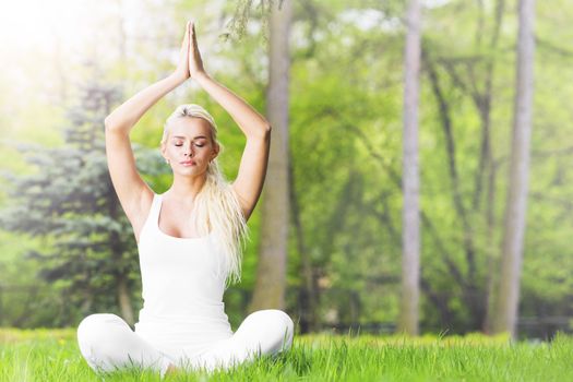 Young girl doing lotus yoga exercise in spring park
