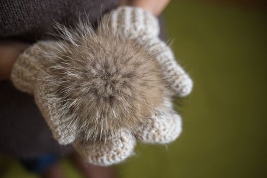 Woman wearing a knitted gloves holding a pompom