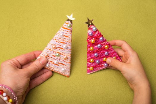 Christmas tree made of threads and beads.in the hands holding the girl