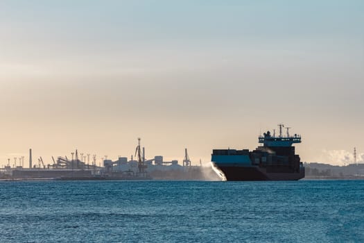 Full red container ship moving in still water