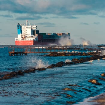 Full red container ship moving in stormy weather