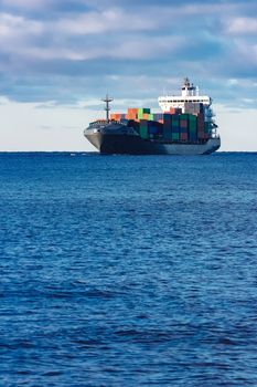 Modern grey container ship moving in still water