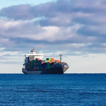 Modern grey container ship moving in still water