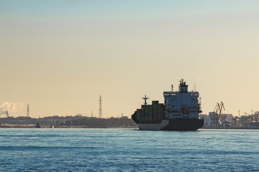 Modern grey container ship moving in still water