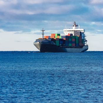 Modern grey container ship moving in still water