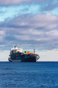 Modern grey container ship moving in still water