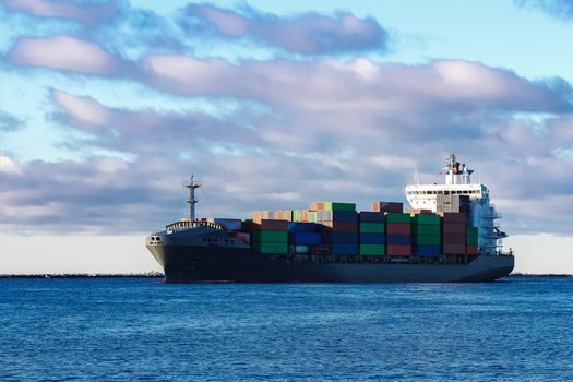 Modern grey container ship moving in still water