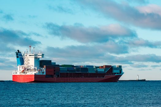 Full red container ship moving in still water