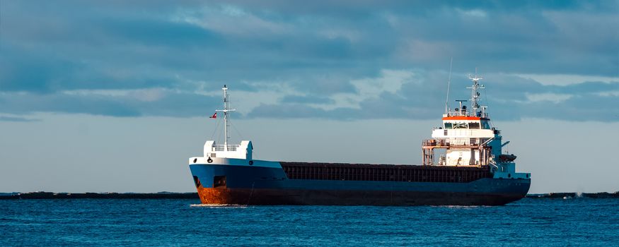 Blue bulk carrier sailing in still water