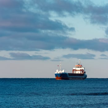 Blue bulk carrier sailing in still water