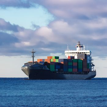 Modern grey container ship moving in still water