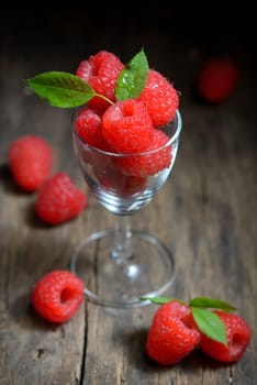 Raspberries in small glass on wooden table