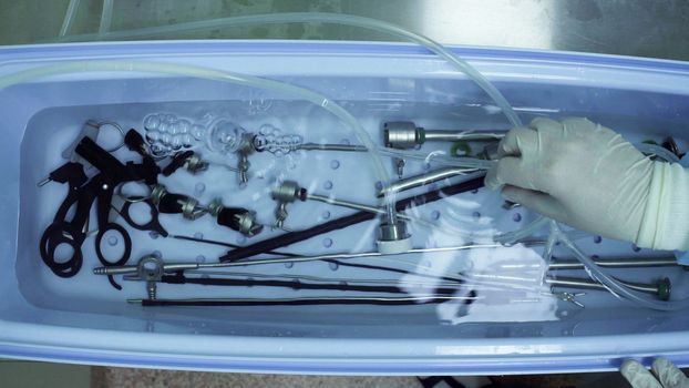 Close up of nurse's hands washing medical instrument after operation