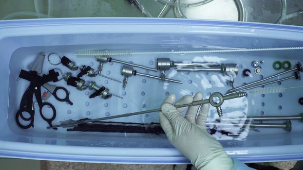 Close up of nurse's hands washing medical instrument after operation